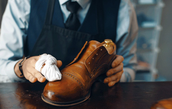 Une personne nettoyant une chaussure en cuir